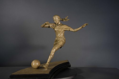 Bronze sculpture of young woman playing soccer