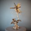 Bronze sculpture of a fairy with butterfly wings on top of a flower - back side