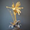 Bronze sculpture of a fairy covered in gold leaf with butterfly wings on top of a flower - front