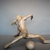 Bronze sculpture of a woman soccer player slide tackling the ball - right side view