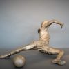 Bronze sculpture of a woman soccer player slide tackling the ball - right side view