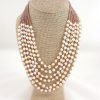 Collar Necklaces displayed on a beige bust, featuring multiple strands with alternating rows of white pearls and small light brown beads.